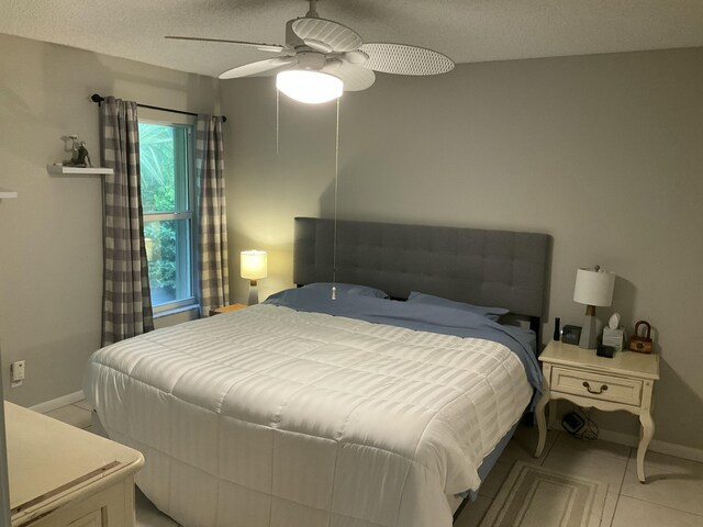 tiled bedroom with ceiling fan, multiple windows, and a textured ceiling