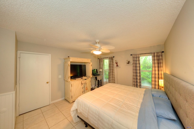 tiled bedroom featuring ceiling fan and a textured ceiling