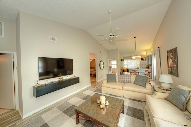 living room with ceiling fan, lofted ceiling, and light wood-type flooring