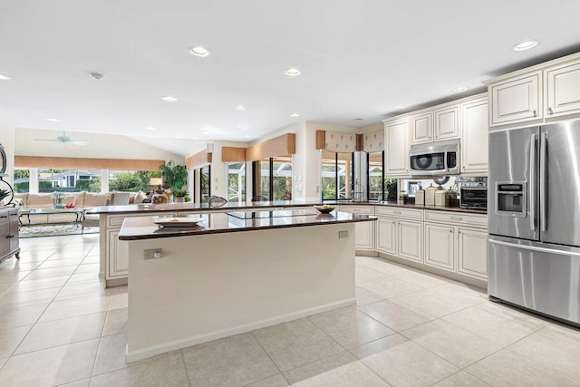 kitchen with vaulted ceiling, light tile patterned flooring, a center island, and appliances with stainless steel finishes