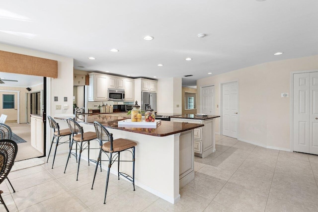 kitchen with light tile patterned floors, a breakfast bar area, ceiling fan, appliances with stainless steel finishes, and kitchen peninsula