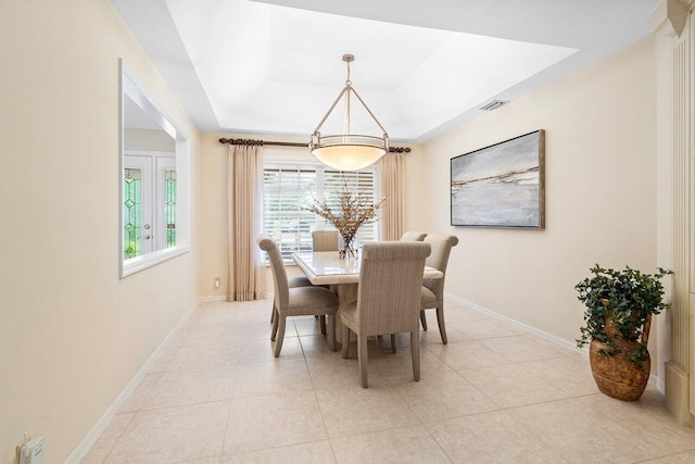 tiled dining area with a tray ceiling