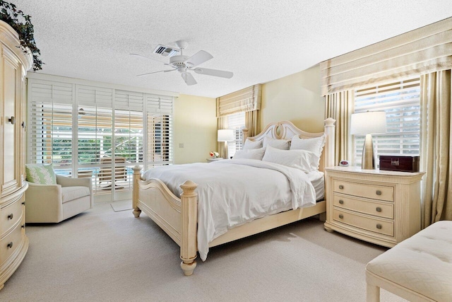 bedroom with light carpet, a textured ceiling, and ceiling fan