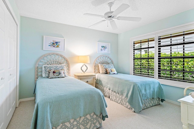 carpeted bedroom with ceiling fan, a closet, and a textured ceiling