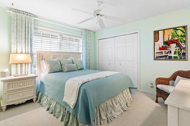 carpeted bedroom featuring ceiling fan, a closet, and a textured ceiling