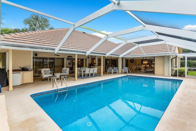 view of pool with a patio area, an outdoor kitchen, and glass enclosure