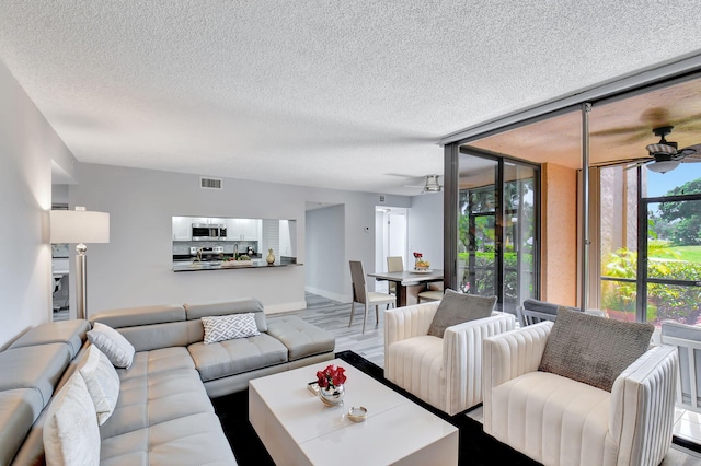 living room with hardwood / wood-style floors, a textured ceiling, and ceiling fan