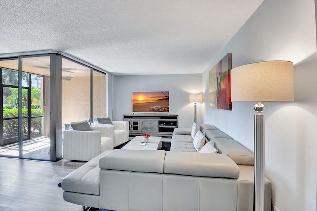 living room with a wall of windows, a textured ceiling, and light hardwood / wood-style floors