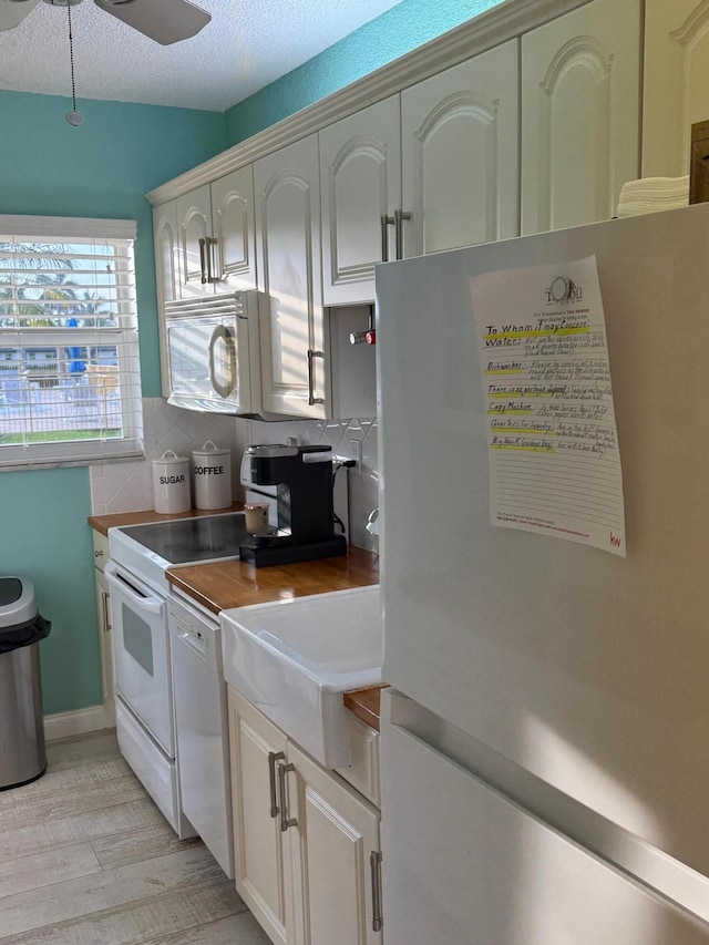 kitchen featuring ceiling fan, white appliances, a textured ceiling, and white cabinets