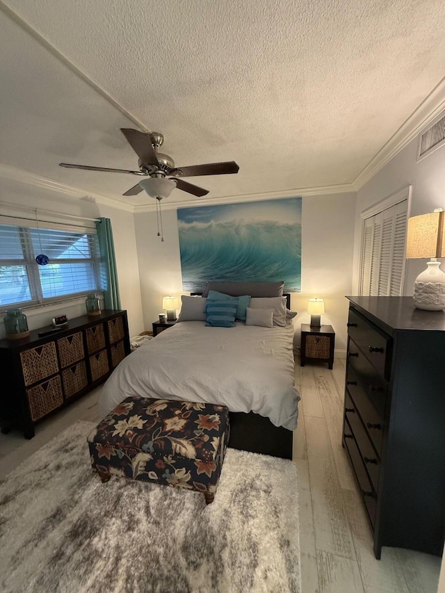 bedroom with crown molding, ceiling fan, light hardwood / wood-style floors, and a textured ceiling