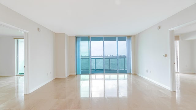 tiled spare room with a water view and expansive windows