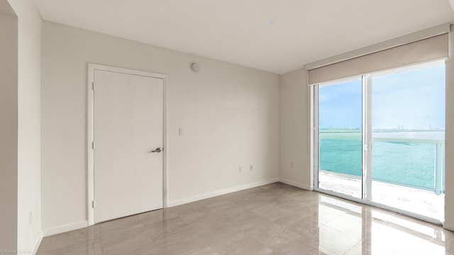 unfurnished room featuring light tile patterned flooring and a water view