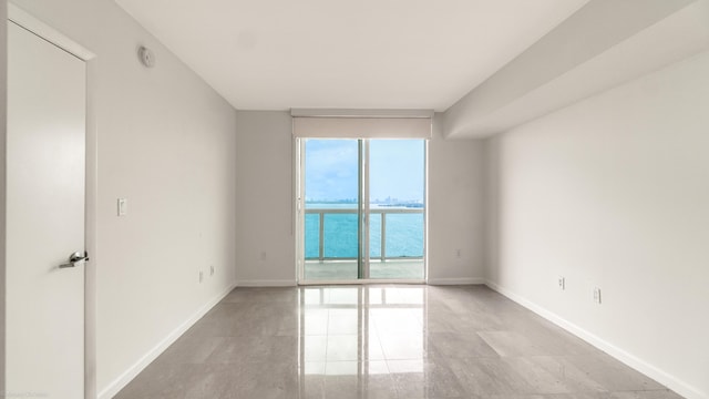 unfurnished room with expansive windows and a water view