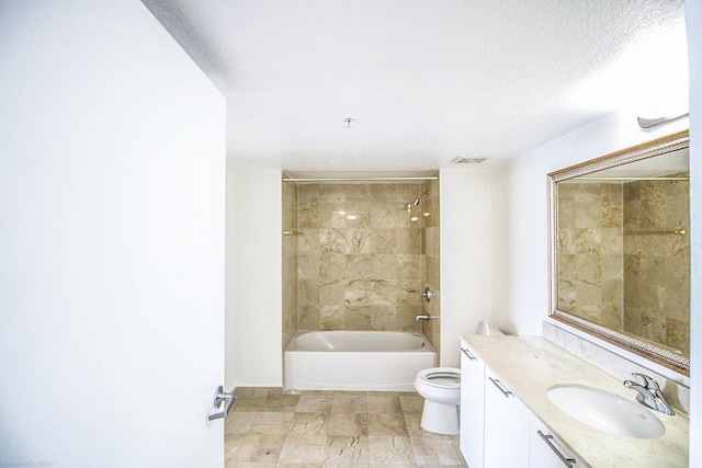 full bathroom featuring a textured ceiling, tiled shower / bath combo, vanity, and toilet