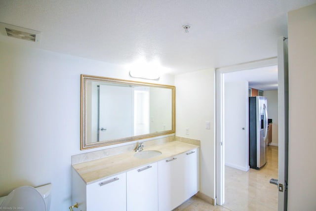 bathroom with a textured ceiling, vanity, and toilet