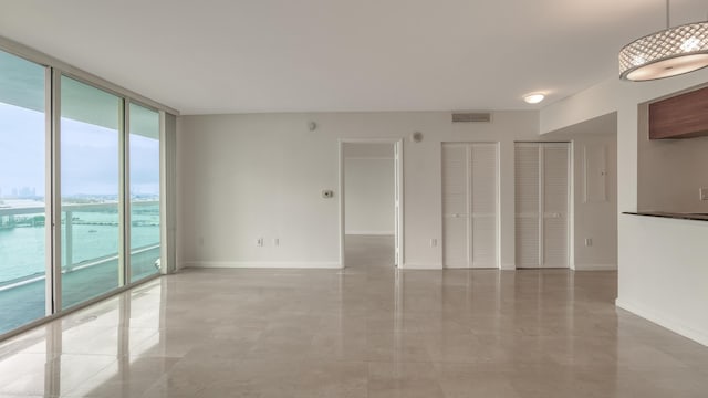 spare room with floor to ceiling windows and a water view