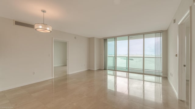 spare room featuring expansive windows and a water view