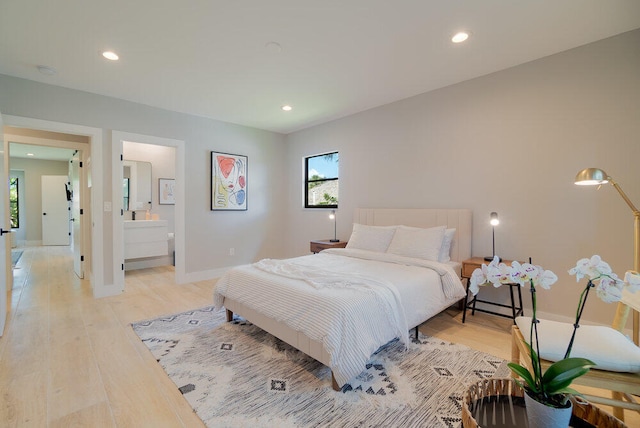 bedroom with ensuite bathroom and light hardwood / wood-style flooring