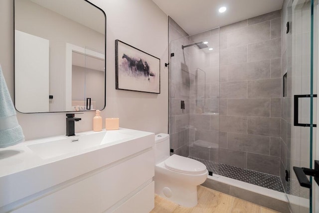 bathroom with toilet, vanity, walk in shower, and hardwood / wood-style flooring