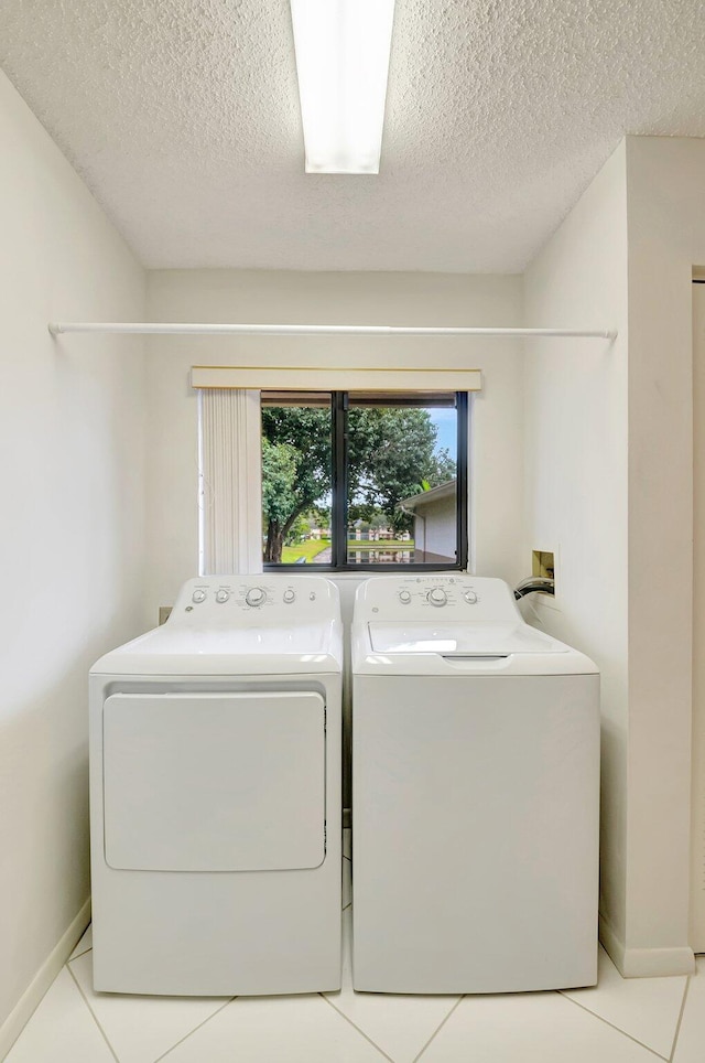 15144 Ashland St Unit 295, Delray Beach, FL 33484 - laundry area with a textured ceiling, light tile patterned flooring, washing machine and dryer, baseboards, and laundry area