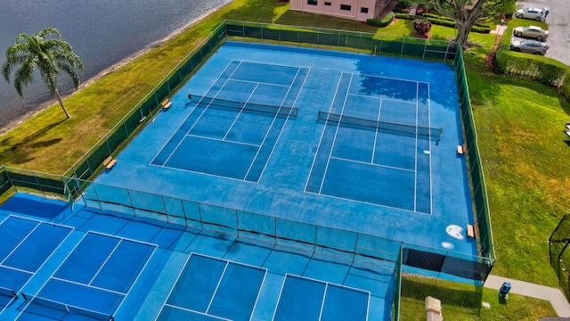 view of tennis court with fence and a water view