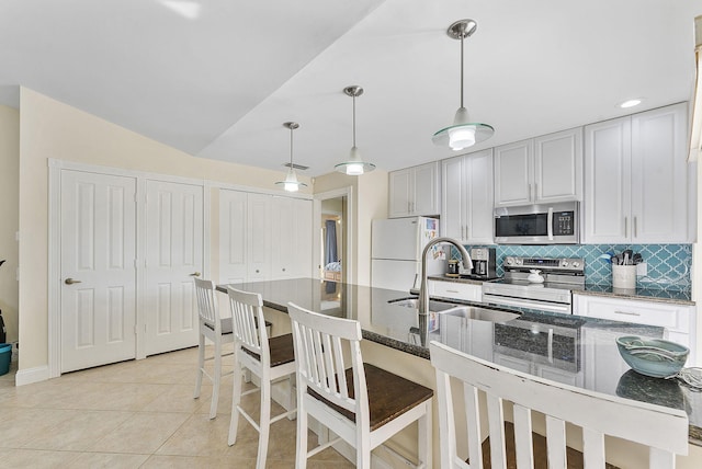 kitchen with dark stone countertops, pendant lighting, sink, appliances with stainless steel finishes, and light tile patterned floors