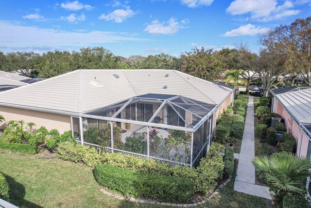 rear view of house featuring a yard and glass enclosure