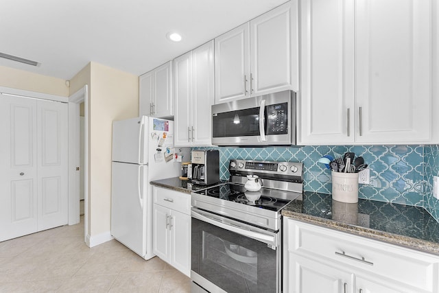 kitchen featuring white cabinets, appliances with stainless steel finishes, dark stone counters, tasteful backsplash, and light tile patterned floors