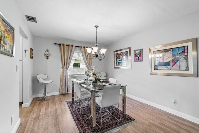 dining space featuring a notable chandelier and light wood-type flooring