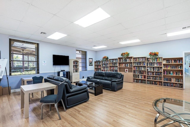 living room featuring a drop ceiling and light hardwood / wood-style flooring