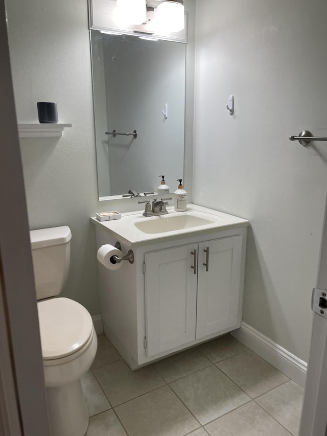 bathroom with toilet, vanity, and tile patterned flooring