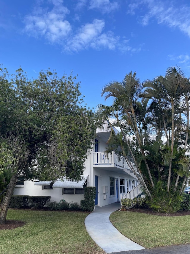 view of front facade featuring a front lawn and a balcony