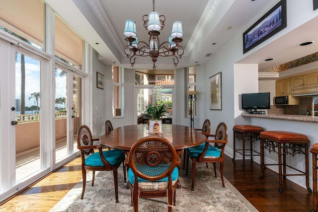 dining area featuring a raised ceiling, an inviting chandelier, and ornamental molding