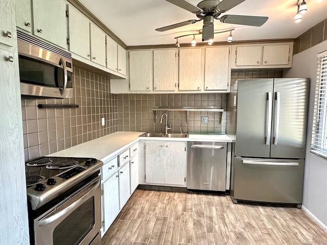 kitchen with ceiling fan, appliances with stainless steel finishes, decorative backsplash, light wood-type flooring, and sink