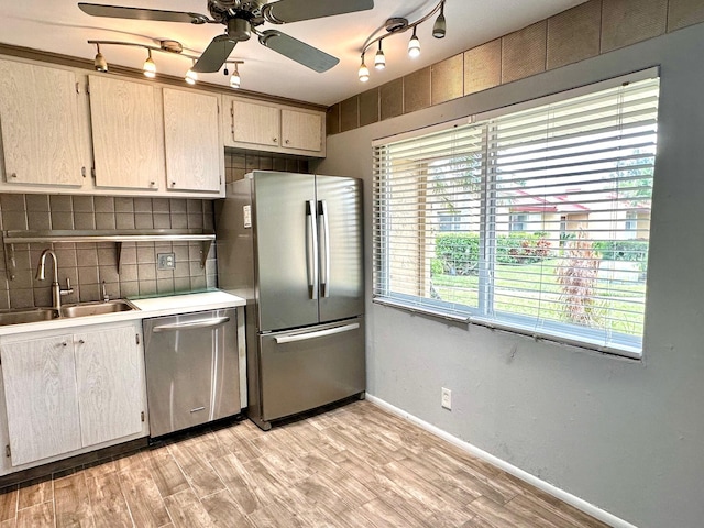 kitchen featuring appliances with stainless steel finishes, decorative backsplash, sink, light hardwood / wood-style floors, and ceiling fan