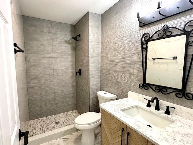 bathroom with toilet, tiled shower, and vanity