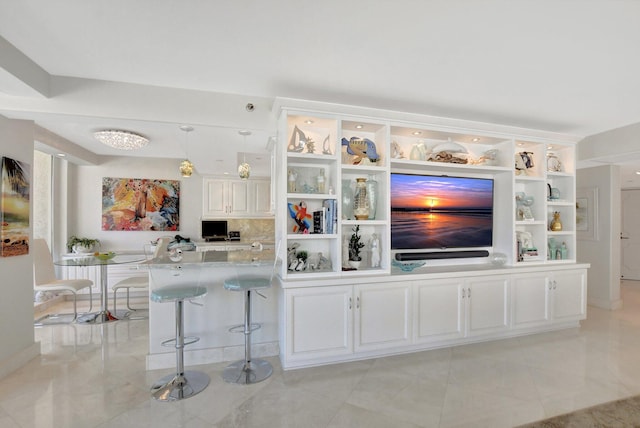 bar with light tile patterned floors, white cabinets, light stone counters, and decorative light fixtures