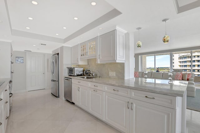 kitchen featuring a tray ceiling, white cabinets, appliances with stainless steel finishes, and kitchen peninsula