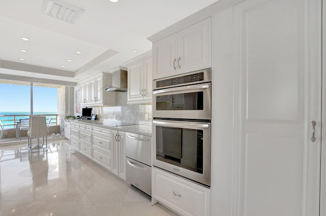 kitchen featuring white cabinets, double oven, black electric cooktop, and wall chimney exhaust hood