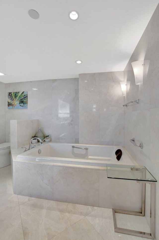 bathroom with toilet and tiled bath