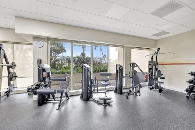 exercise room featuring a paneled ceiling and a healthy amount of sunlight