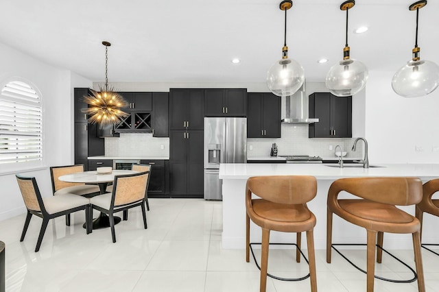 kitchen with sink, wall chimney exhaust hood, stainless steel fridge with ice dispenser, and pendant lighting