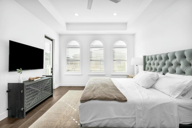 bedroom featuring ceiling fan, a raised ceiling, and dark hardwood / wood-style floors