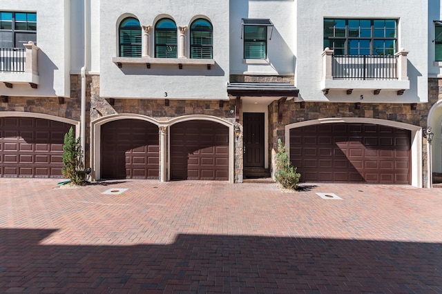 view of front facade with a garage, driveway, and stucco siding