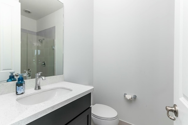 bathroom featuring toilet, a shower with shower door, and vanity