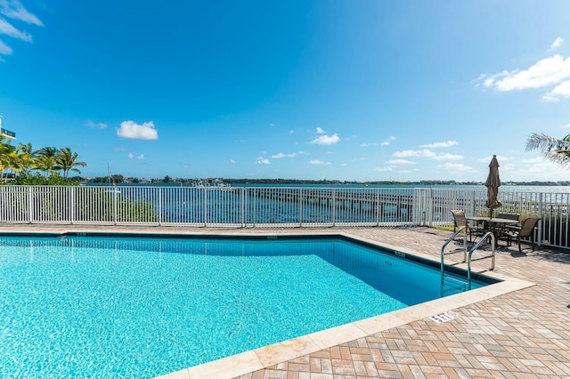 view of pool featuring a water view and a patio area