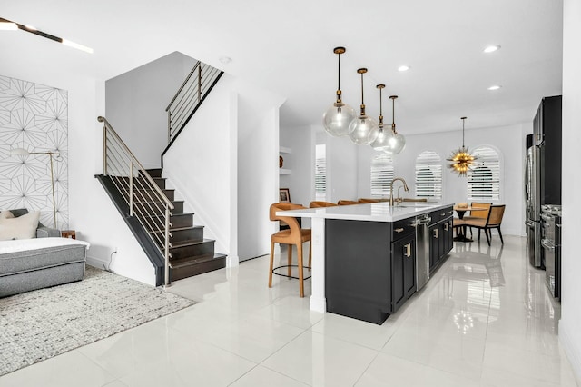 kitchen featuring plenty of natural light, sink, a center island with sink, and decorative light fixtures