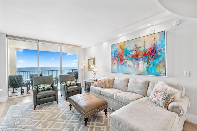 living room featuring floor to ceiling windows, wood-type flooring, and a water view