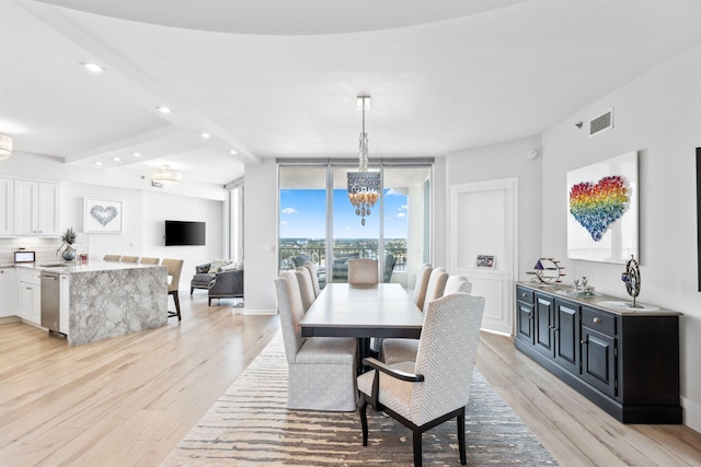 dining room with light hardwood / wood-style floors, expansive windows, beam ceiling, and a notable chandelier