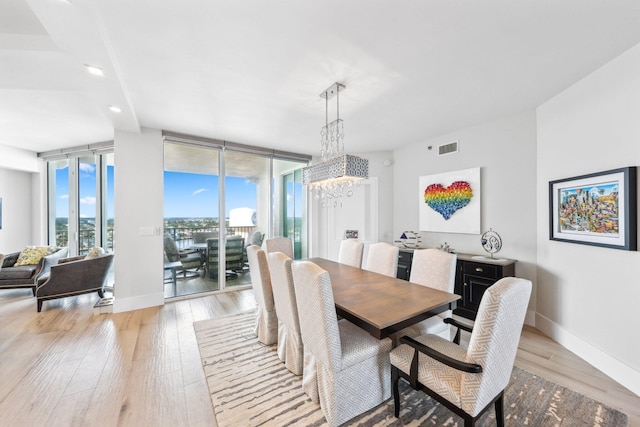 dining space featuring light hardwood / wood-style floors, expansive windows, and a notable chandelier